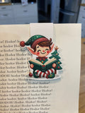 Christmas elf reading magnetic bookmark clipped to a book page
