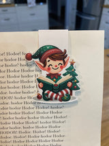 Christmas elf reading magnetic bookmark clipped to a book page