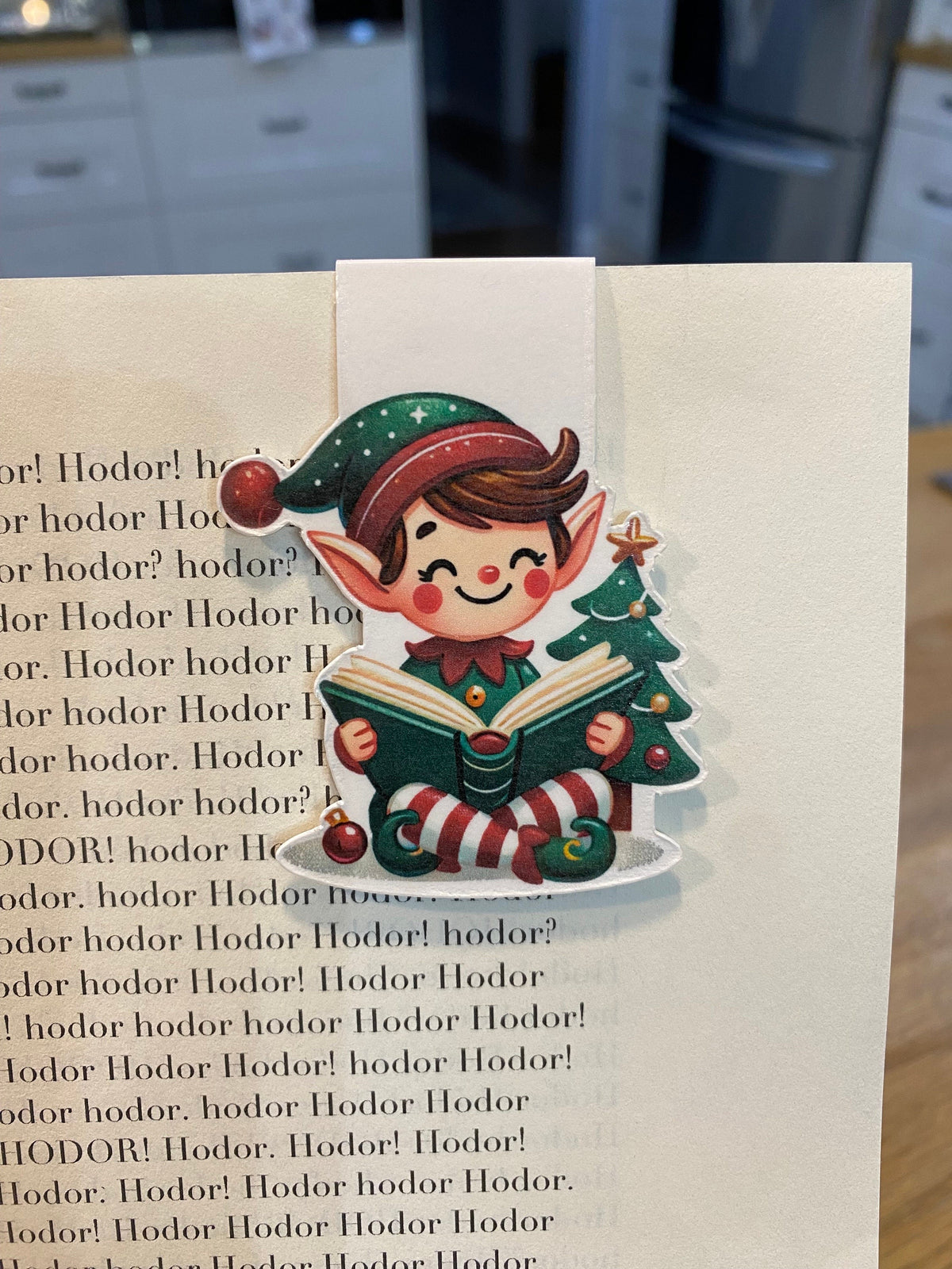 Christmas elf reading magnetic bookmark clipped to a book page