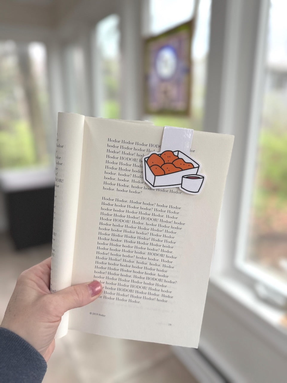 Chicken Nuggets Magnetic Bookmark held in a hand marking a page in an open book