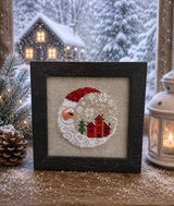 Framed cross-stitch, Santa Christmas Village, dark brown frame close-up