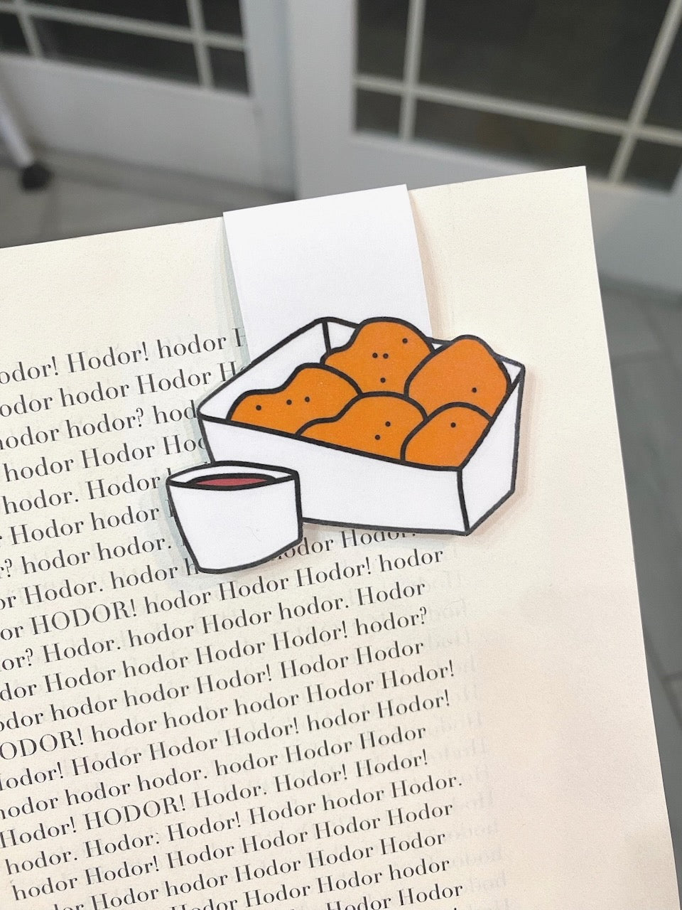 Chicken Nuggets Magnetic Bookmark clipped over a book page corner, detail view of nuggets and sauce cup