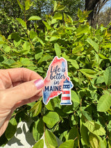 Maine state pride vinyl sticker held up outdoors, close-up angle